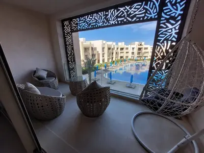 a room with chairs and a window with a view of a pool at MCJ Luxury 2 Bedrooms Apartment in Hurghada