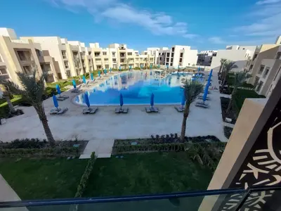 a large swimming pool with palm trees and buildings at MCJ Luxury 2 Bedrooms Apartment in Hurghada