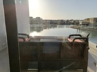 a balcony with a table and chairs and a large window at Tawila, 4 Bedroom Villa, Brand new, directly on a lagoon in Hurghada
