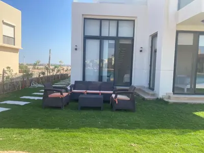 a group of chairs sitting on the grass in front of a house at Tawila, 4 Bedroom Villa, Brand new, directly on a lagoon in Hurghada