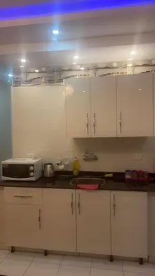 a kitchen with white cabinets and a microwave at Hossam Comfort Apartment El Hadaba Hurghada in Hurghada