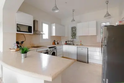 a kitchen with white cabinets and a stainless steel refrigerator at Modern Villa in El Gouna (Private Pool & Garden.) in Hurghada