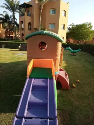a playground with a slide in a yard with a building at Апартаменты в Хургаде, Stella Makadi in Hurghada