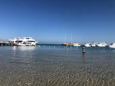 a man standing in the water with boats in the water at Red Sea Tiba plaza Apartment in Hurghada