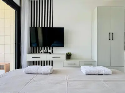 a white bedroom with a tv and a bed at Cozy Studio Apt @ G-cribs El Gouna with a View. in Hurghada