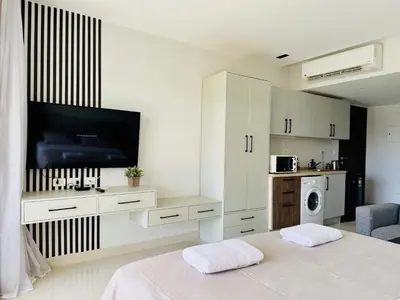 a white room with a bed and a tv at Cozy Studio Apt @ G-cribs El Gouna with a View. in Hurghada