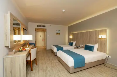 a hotel room with two beds and a desk at Seven Seas Jolie Bay - Ultra All Inclusive in Hurghada