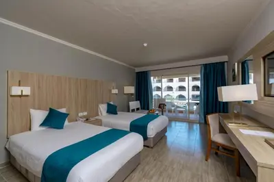 a hotel room with two beds and a desk at Seven Seas Jolie Bay - Ultra All Inclusive in Hurghada