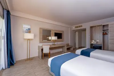a hotel room with two beds and a desk at Seven Seas Jolie Bay - Ultra All Inclusive in Hurghada