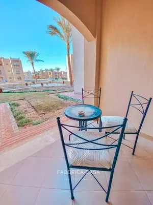 two chairs and a table on a balcony with palm trees at Beautiful 1 bedroom apartment in Quseir
