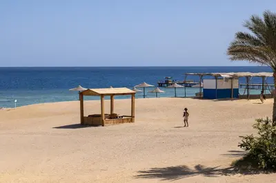 a person walking on a sandy beach near the ocean at Bliss Nada Beach Resort in Coraya Bay