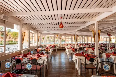 a dining room with tables and chairs and windows at Sentido Caribbean World Soma Bay in Hurghada
