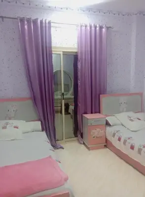 two beds in a room with purple curtains at Yasin - Enjoy the privacy of staying in a quiet apartment with free Wi-Fi as your complete second home in the heart of Hurghada in Hurghada