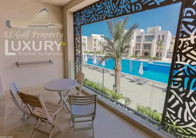 a balcony with a table and chairs and a view of a pool at Mangarov-2BR. M1-6b-12 in Hurghada