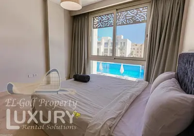 a bedroom with a bed with a chair and a window at Mangarov-2BR. M1-6b-12 in Hurghada