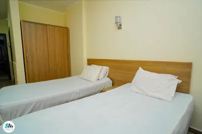 two beds in a hotel room with white sheets at Florenza khamsin home Hurghada in Hurghada