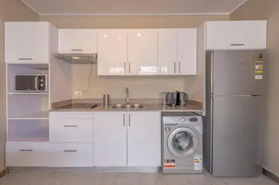 a kitchen with white cabinets and a washing machine at Modern 1 Bedroom Apartment Bali El Gouna Private Patio & Heated Pool in Hurghada