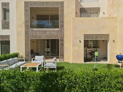 a patio with chairs and tables in front of a building at Ollystays Mangroovy Seaview 3BR Beach and Pool Free access in Hurghada
