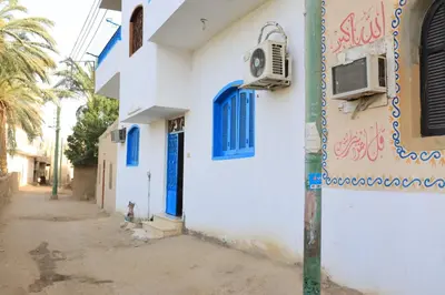 a white building with blue windows and an air conditioner at Ahmed Mulatam House in Luxor