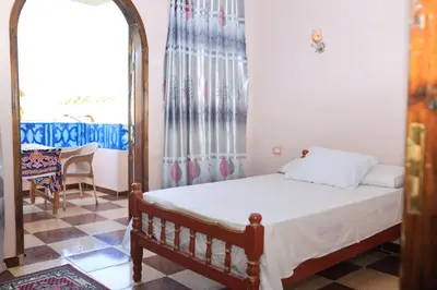 a small bedroom with a bed and a table at Ahmed Mulatam House in Luxor