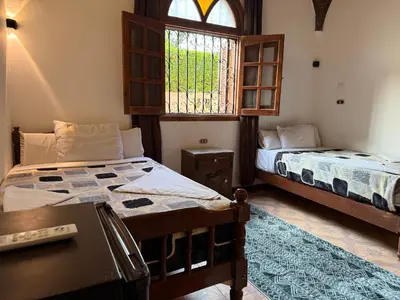 a bedroom with two beds and a window at Luxor Villa Hatshepsut in Luxor