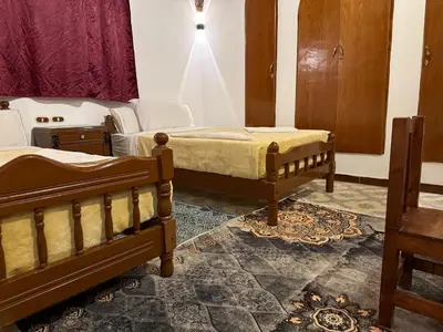 a bedroom with two beds and a table and a window at Luxor Villa Hatshepsut in Luxor
