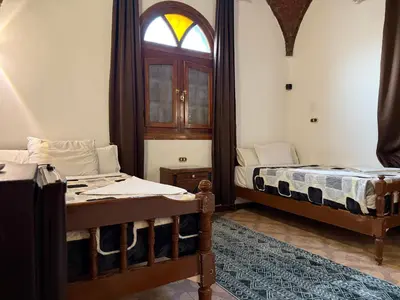 two beds in a room with a window and a room with two beds at Luxor Villa Hatshepsut in Luxor