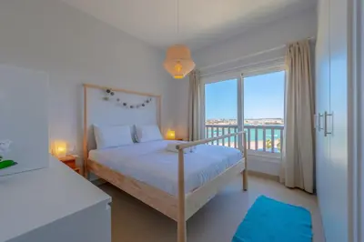 a bedroom with a bed and a large window at Sunny 2 Bedroom + Private Roof Terrace Lagoon View in Hurghada