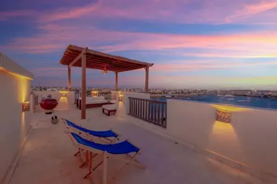 a balcony with two blue chairs on a roof at Sunny 2 Bedroom + Private Roof Terrace Lagoon View in Hurghada