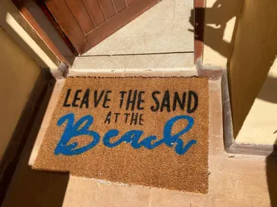 a welcome mat with the words leave the sand at the beach at Lovely two bedroom apartment in Hurghada