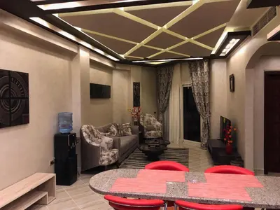 a living room with a table and red chairs at VIVA Andalouse luxury family suite, private beach & pool, NO ORFI in Hurghada