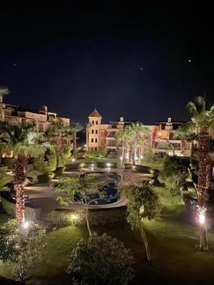 a resort at night with a fountain and palm trees at Apartman Veranda in Hurghada