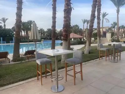 a group of tables and chairs next to a pool at Apartman Veranda in Hurghada