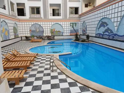 a swimming pool with two chairs and a tile wall at sheraton blaza329 in Hurghada