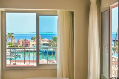 a window with a view of the pool and ocean at AJIRA Bay Hotel Hurghada Marina in Hurghada