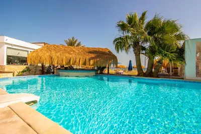a large blue swimming pool with a straw roof at AJIRA Bay Hotel Hurghada Marina in Hurghada