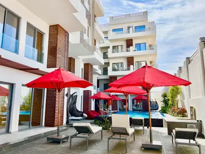 a patio with red umbrellas and a swimming pool at Imperial Resort Hurghada in Hurghada