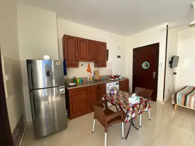 a kitchen with a stainless steel refrigerator and a table at Чудесная студия в комплексе с бассейном рядом с бесплатным пляжем in Hurghada