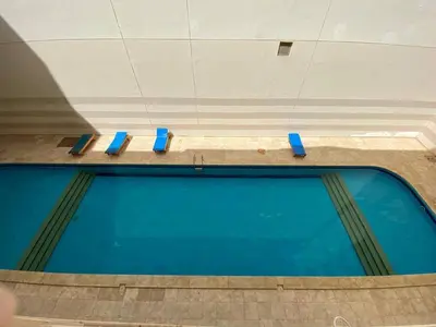 a swimming pool with blue seats in a building at Чудесная студия в комплексе с бассейном рядом с бесплатным пляжем in Hurghada