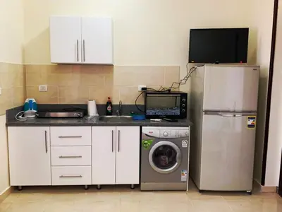 a kitchen with a washing machine and a tv at Прекрасная студия в комплексе с бассейном рядом с бесплатным пляжем in Hurghada