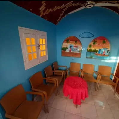 a room with a table and chairs and windows at Aziza House in Aswan