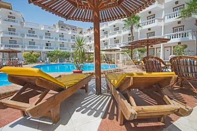 a patio with tables and umbrellas next to a pool at Zak Inn in Hurghada