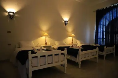 a bedroom with two beds and two tables and two lamps at Luxor Oasis Guest House in Luxor