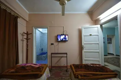 a bedroom with two beds and a tv on the wall at Fontana Hostel luxor in Luxor
