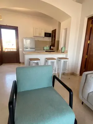 a living room with a chair and a kitchen at Sabina 2br penthouse in Hurghada