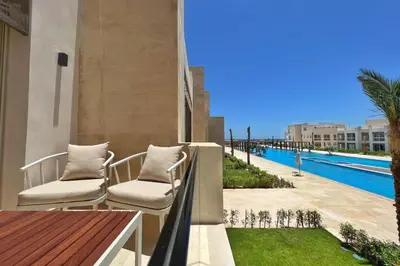 a balcony with two chairs and a swimming pool at Boho Mint 1 BDR Mangroovy Pool & Sea View in Hurghada