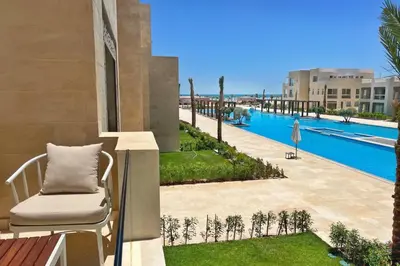 a balcony with a chair and a swimming pool at Boho Mint 1 BDR Mangroovy Pool & Sea View in Hurghada