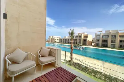 a balcony with two chairs and a view of a pool at Boho Mint 1 BDR Mangroovy Pool & Sea View in Hurghada