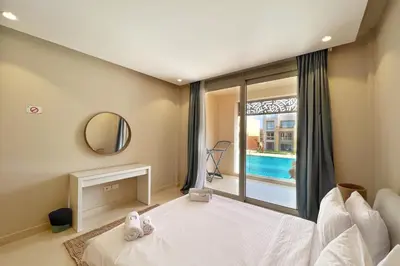 a bedroom with a bed and a window with a pool at Boho Mint 1 BDR Mangroovy Pool & Sea View in Hurghada