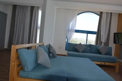 a living room with a blue couch and a large window at La Casa Beach in Hurghada